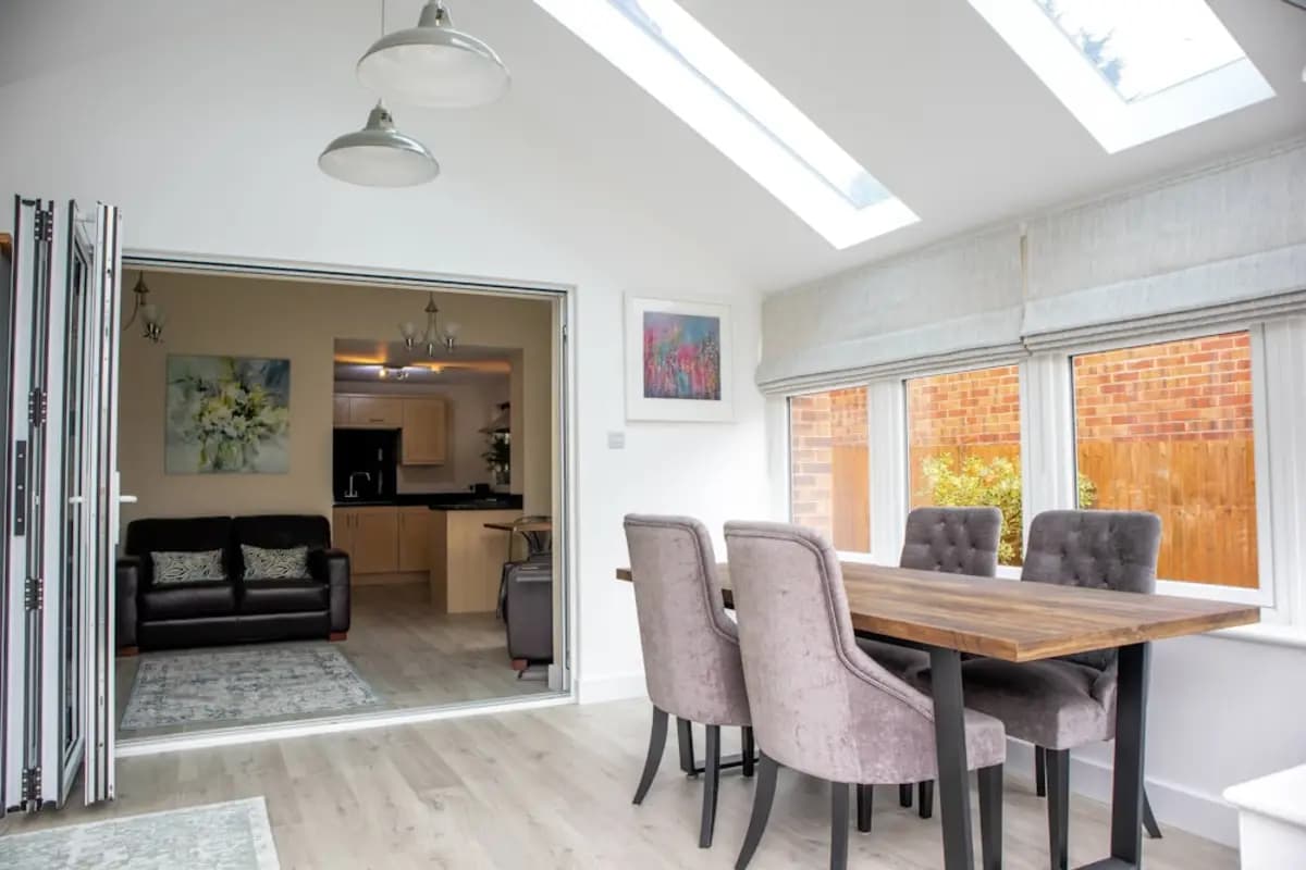 A dining room opening into a kitchen through wide glazed doors