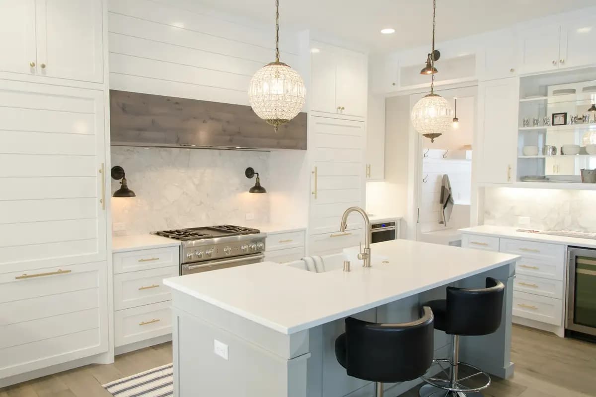A finished kitchen with an island, pendant lights and a marble splashback