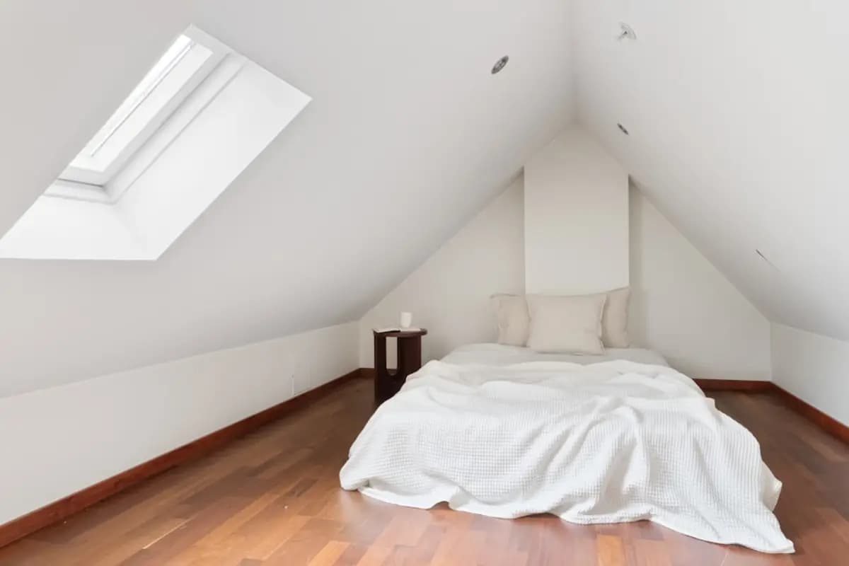 A converted loft bedroom under a sloped ceiling with a rooflight